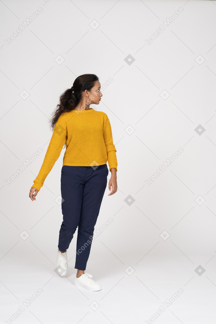 Front view of a girl in casual clothes walking forward and looking aside