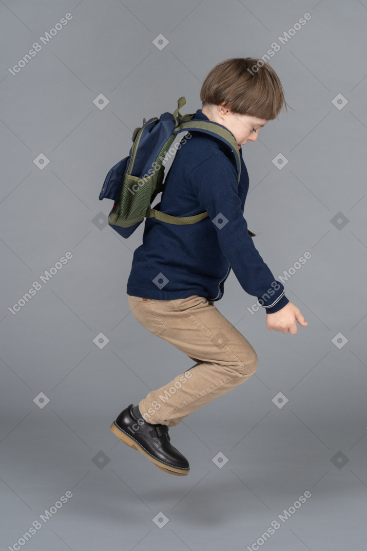 Niño pequeño con una mochila saltando