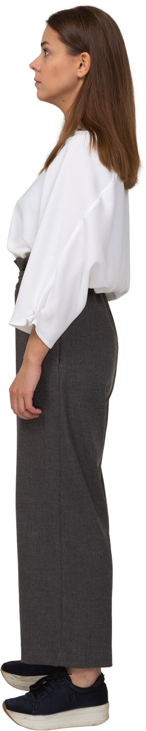 Vista lateral de uma jovem surpresa com roupas de escritório, olhando para o lado
