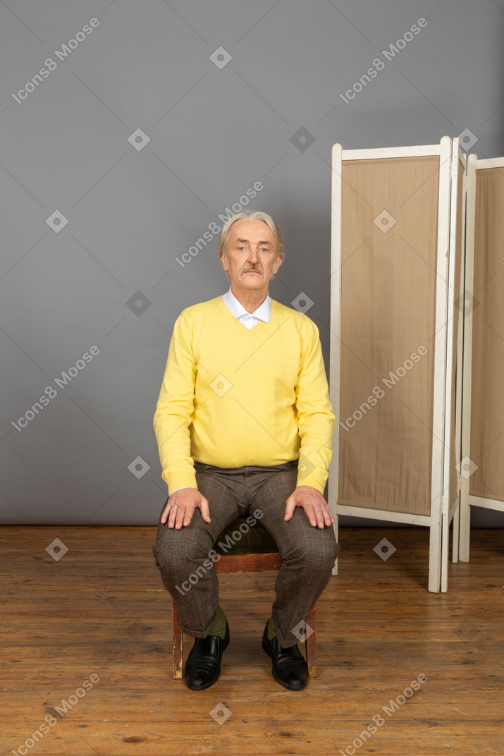 Man sitting with his hands on his hips