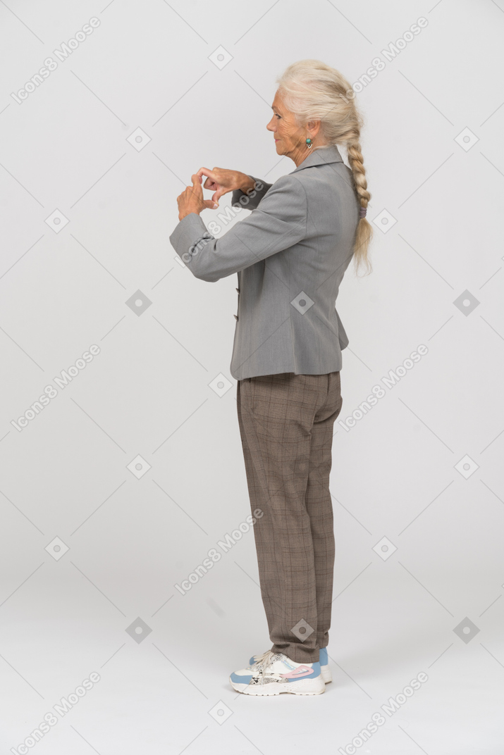 Side view of an old lady in suit making heart sign with her fingers