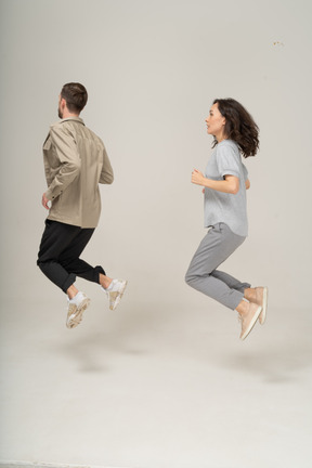 Side view of young woman and man in the air  with bent legs