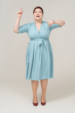 Front view of a happy woman in blue dress dancing