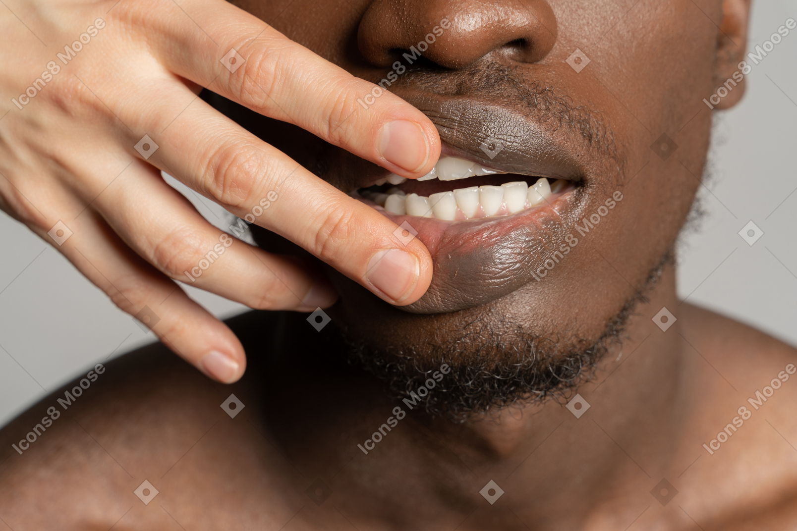 White fingers touching teeth of a black man