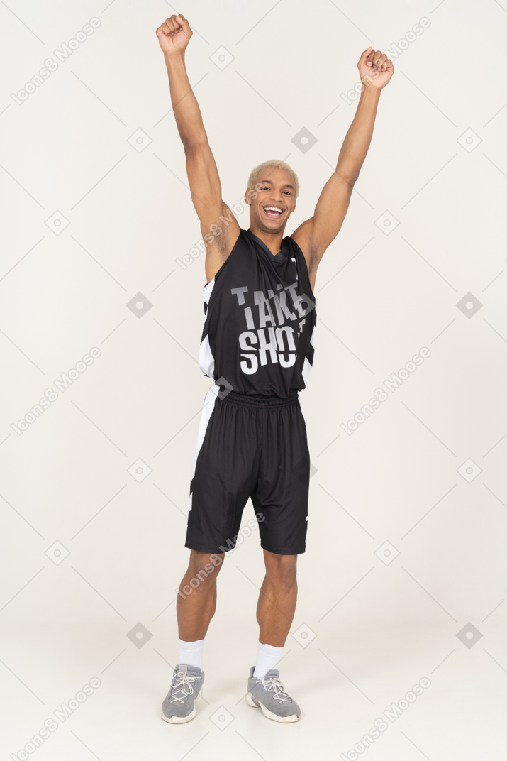 Vista frontal de un joven jugador de baloncesto masculino feliz levantando las manos
