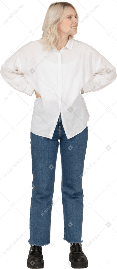 Vista frontale di una donna bionda in abiti casual, mettendo le mani sui fianchi e guardando a destra