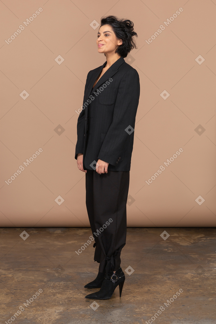 一个女商人，穿着黑西装，显示舌头的四分之三视图