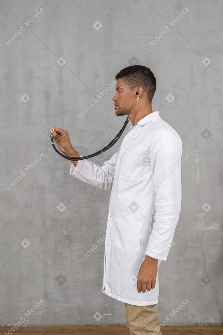 Vue latérale d'un médecin de sexe masculin à l'aide d'un stéthoscope
