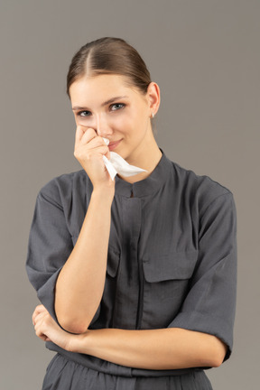 Front view of a young woman in a jumpsuit holding make up removing wipe