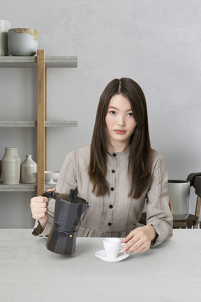 A woman sitting at a table with a cup of coffee