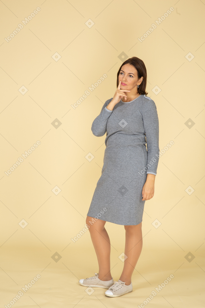 Vista frontale di una donna in abito grigio che pensa