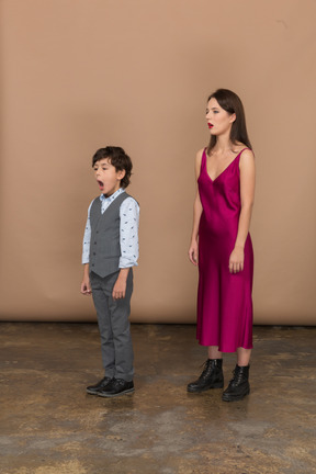 Sleepy woman in red dress and boy in grey suit vest