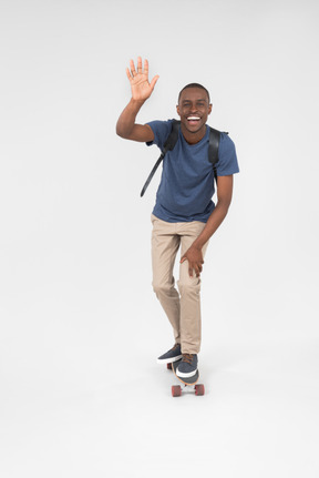 Smiling male tourist standing on skateboard and skating