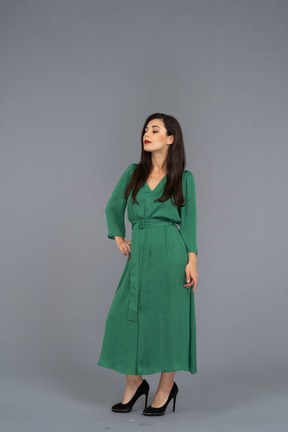 Three-quarter view of a proud young lady in green dress putting hand on hip