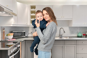 A woman holding a baby in a kitchen