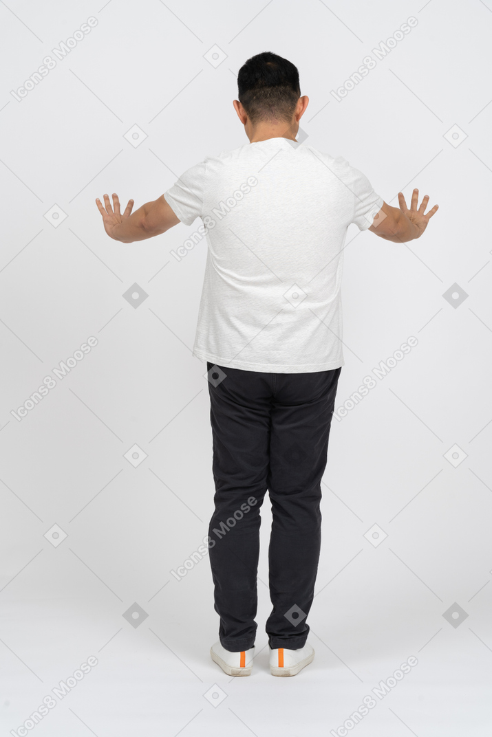 Вид сзади человека в повседневной одежде, стоящего с вытянутыми руками
