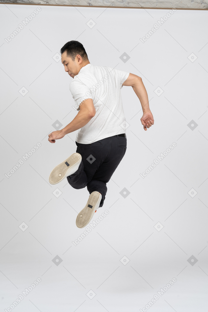高くジャンプするカジュアルな服装の男の背面図