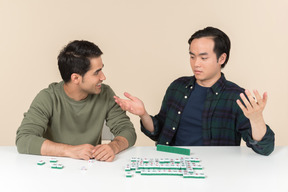 Interracial friends sitting at the table and playing scramble