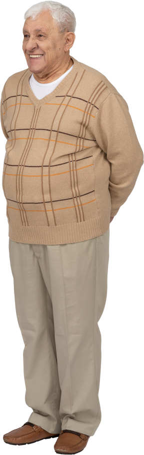 Vista frontal de un anciano feliz con ropa informal de pie con las manos detrás de la espalda