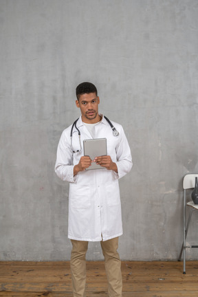 Front view of a male doctor holding a tablet