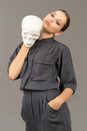 Front view of a young woman in a jumpsuit holding a plaster skull