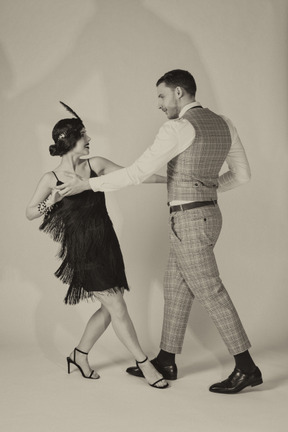 Мужчина и женщина держатся за руки во время танца чарльстон