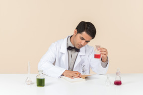 Científico masculino sosteniendo bulbo y sentado en la mesa