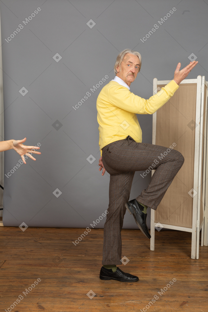 Side view of an old man raising both hand and leg