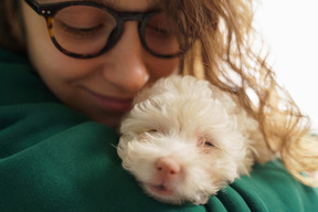 Giovane donna con gli occhiali e coccole con il suo piccolo barboncino