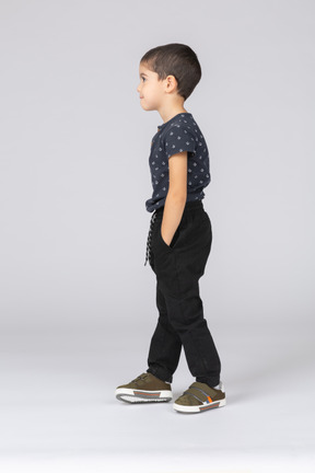 Vue latérale d'un garçon mignon posant avec les mains dans les poches