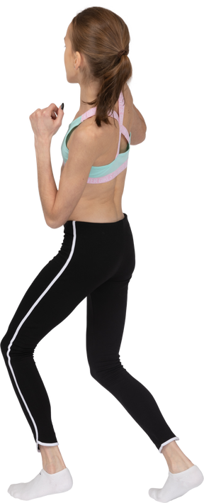 Three-quarter back view of a teen girl in a sportswear making a lunge