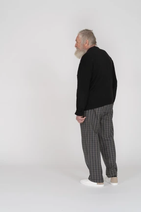 Three-quarter back view of an old bearded man standing