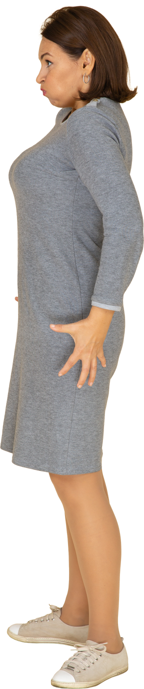 Vista lateral de uma mulher de vestido cinza fazendo caretas