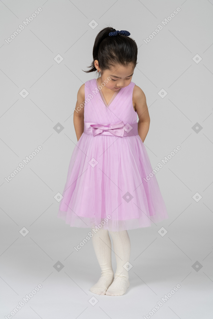 Маленькая девочка в розовом платье смотрит вниз