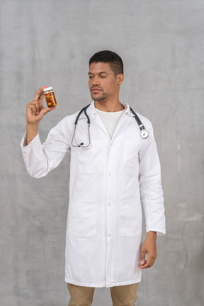 Doctor in lab coat looking at medicine bottle