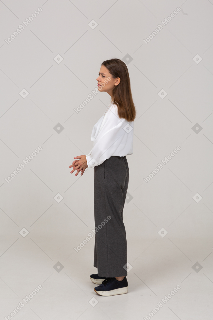 Vista lateral de uma jovem confusa com roupa de escritório, de mãos dadas