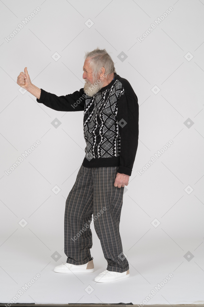 Side view of old man giving thumbs up