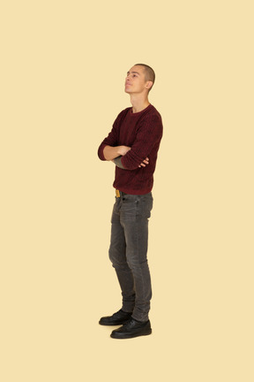 Three-quarter view of an offended young man dressed in casual clothes crossing his hands