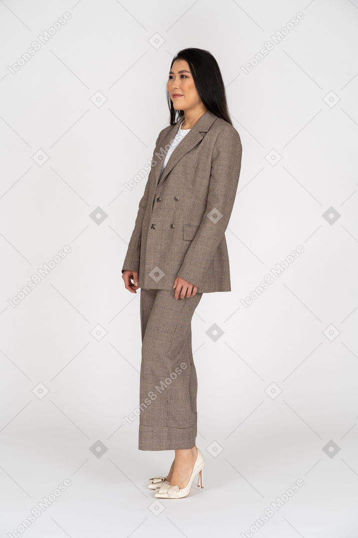 Three-quarter view of a pleased smiling young lady in brown business suit