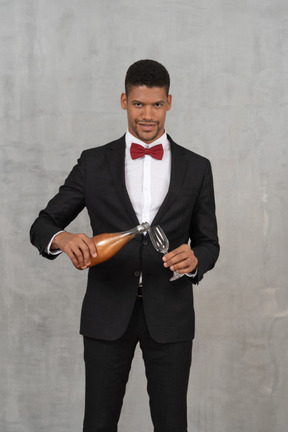 Smiling man filling a champagne glass and looking at camera