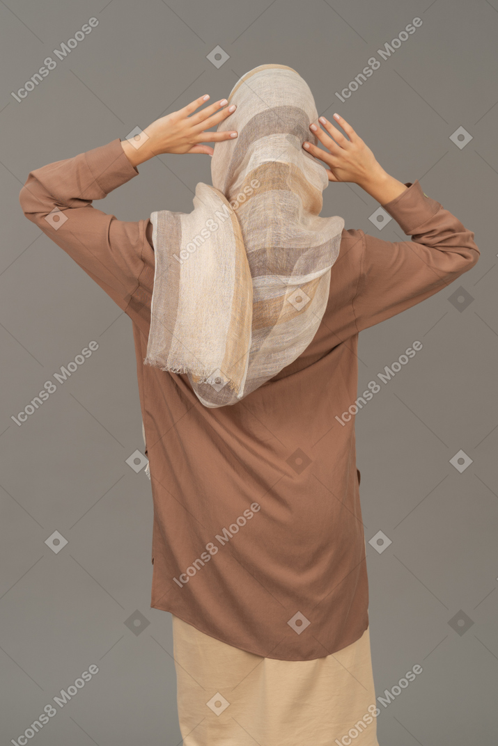 Mulher em roupas tradicionais, segurando as mãos atrás da cabeça