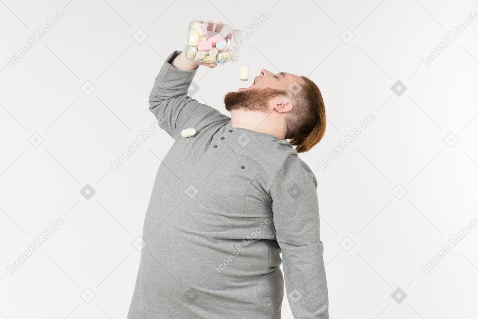 Bid bearded man throwing marshmallows from the jar into a mouth