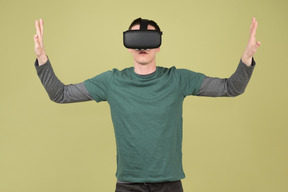 Молодой человек в гарнитуре виртуальной реальности касается воображаемых стен