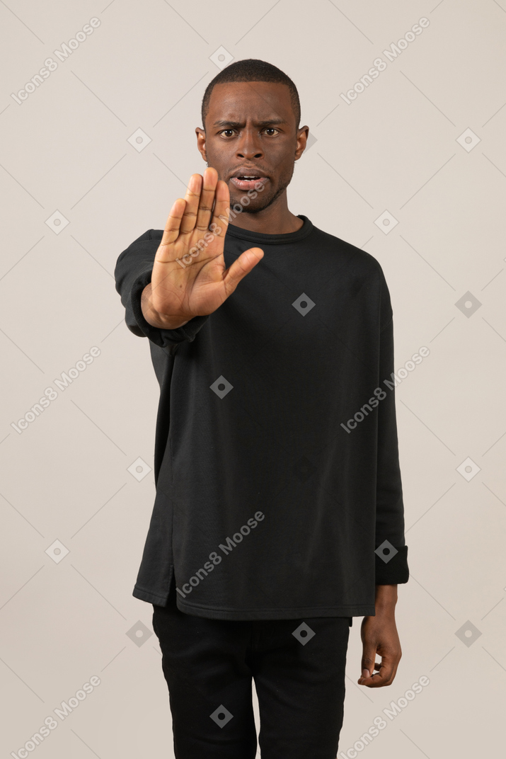 Serious young man stopping someone with hand