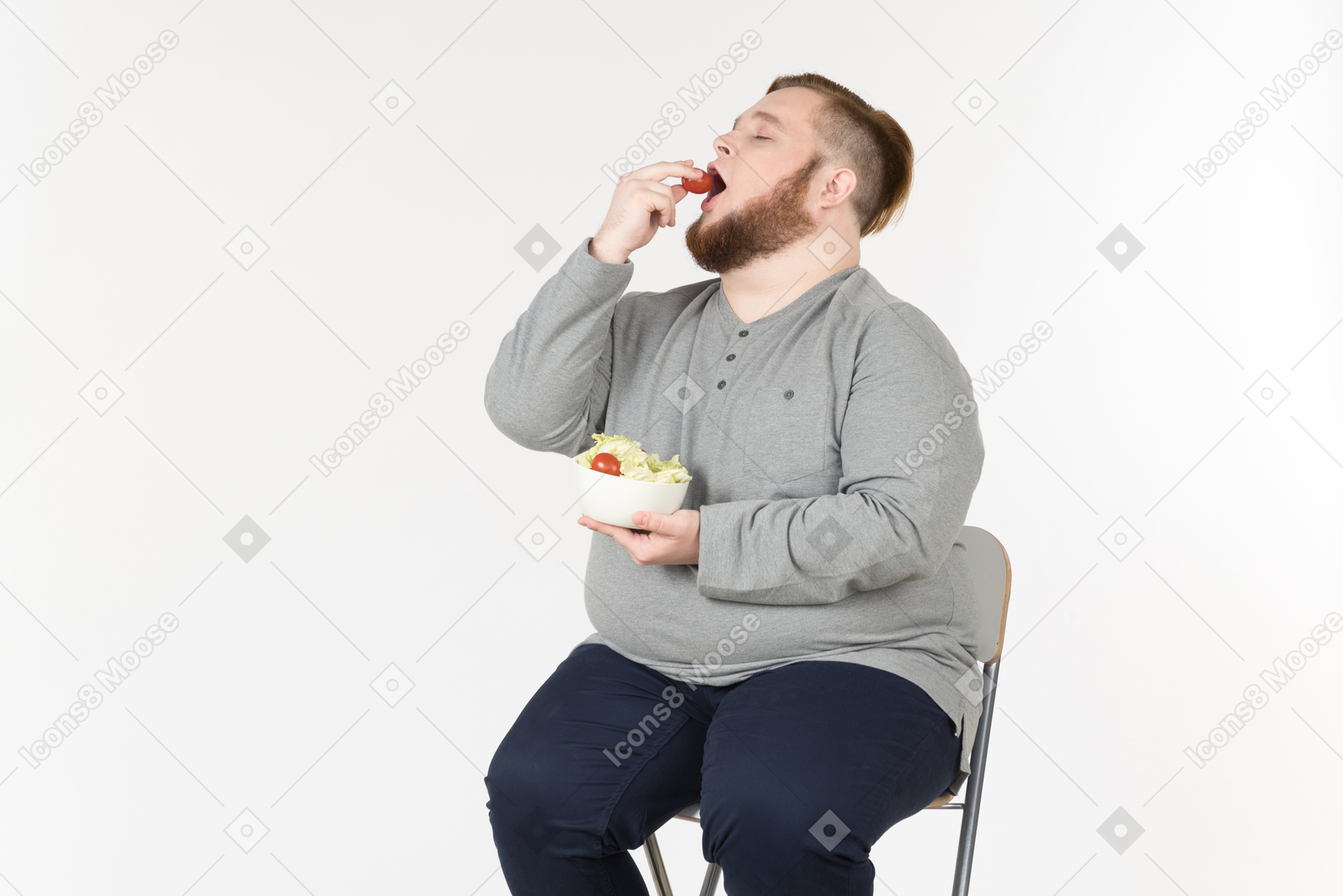 의자에 앉아 샐러드를 먹는 큰 수염 난된 남자