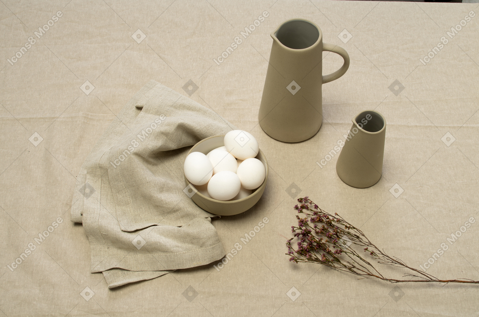 Uma tigela de ovos de galinha e alguns frascos em uma toalha de mesa cinza