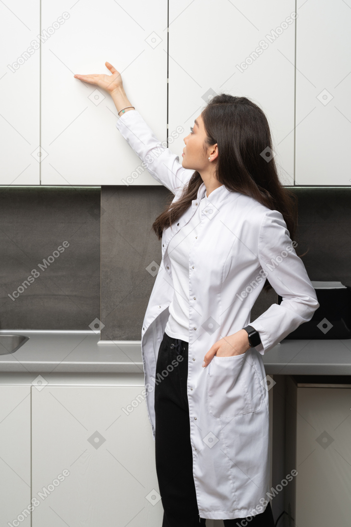 Three-quarter view of a young female doctor observing her medical cabinet
