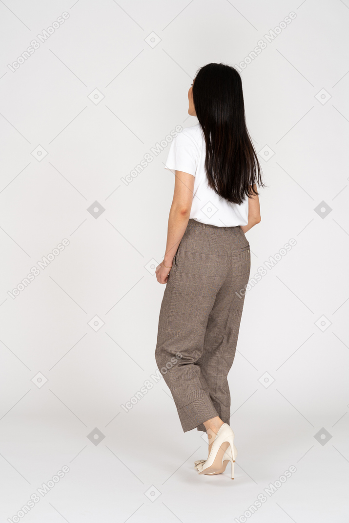 Vista posteriore di tre quarti di una giovane donna che cammina in calzoni e maglietta