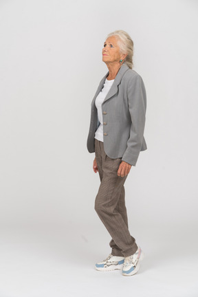 Side view of an old lady in suit standing on one leg