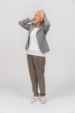 Vista frontal de uma senhora idosa de terno posando com as mãos atrás da cabeça
